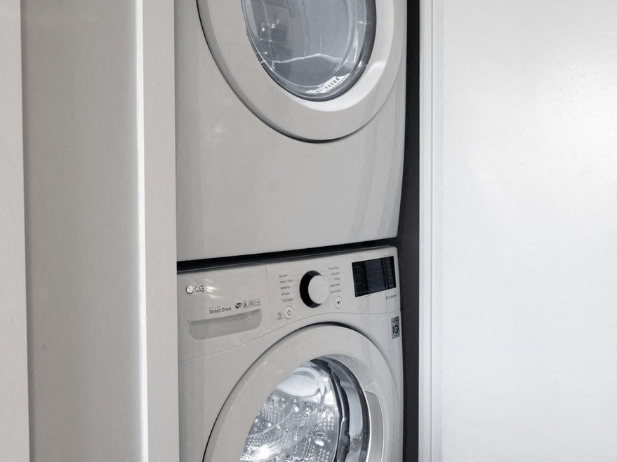 a front loading washer and dryer in a white utility room