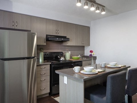 A modern kitchen with a refrigerator, oven, and dining table set for two.