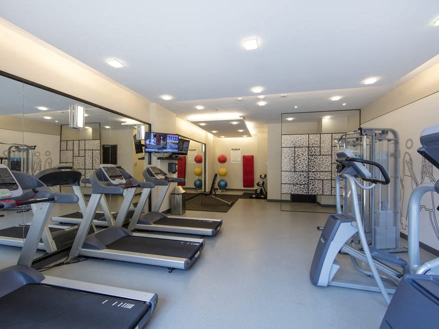 a gym with cardio equipment and a flat screen tv