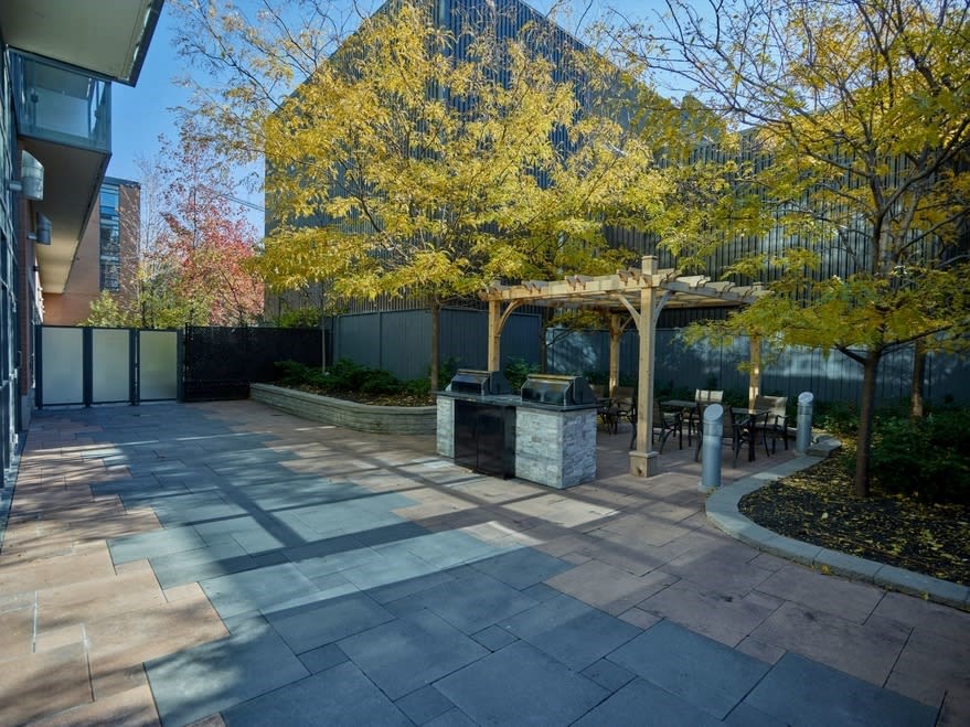a patio with a fire pit and a pergola in front of a building