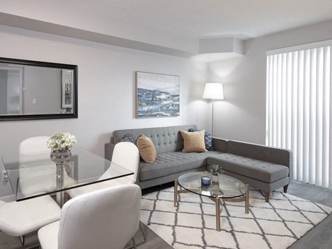 A modern living room with a grey couch, a glass table, and a coffee table with a glass top.