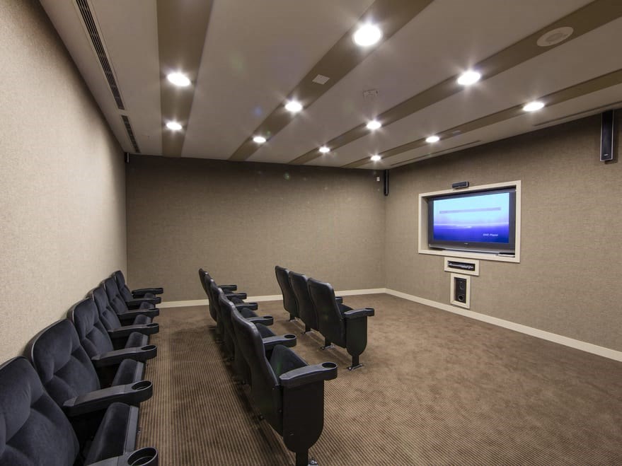a large room with a large screen tv on the wall and a row of black chairs