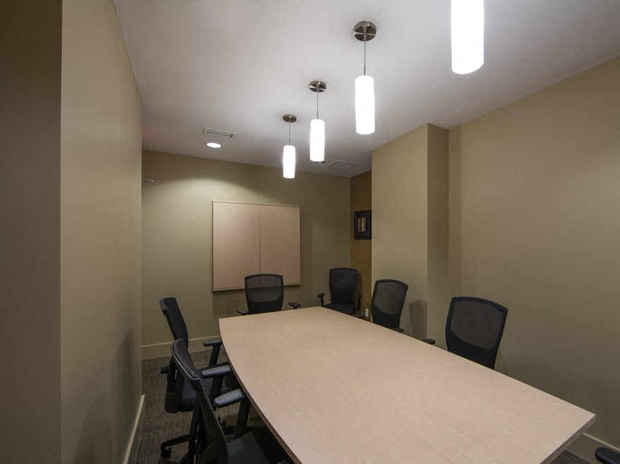 a small conference room with a long table and black chairs