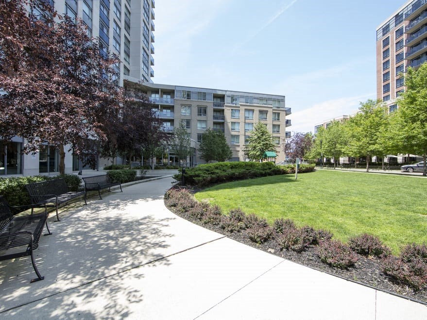 a park with benches and a grassy area in front of a building