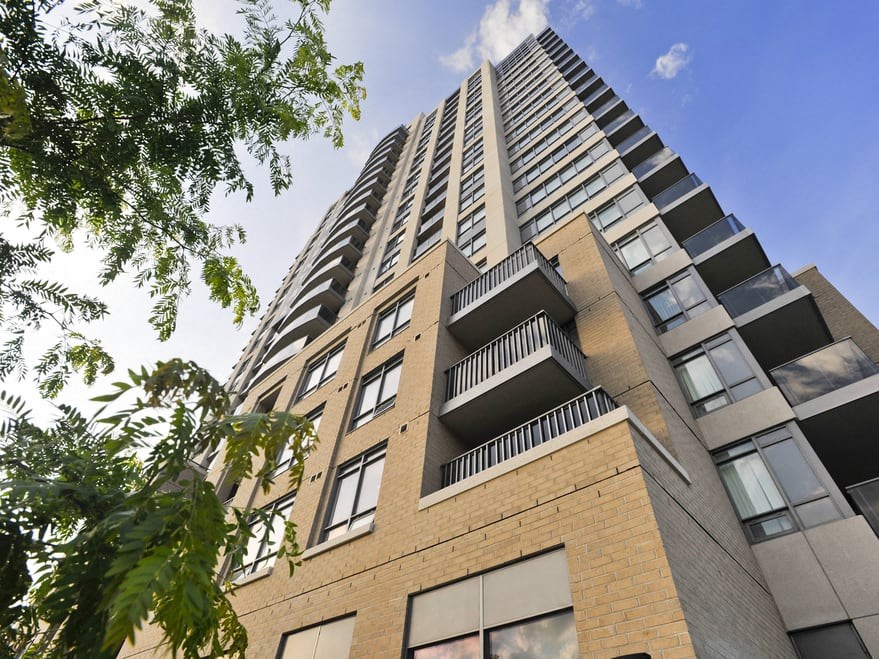 looking up at a tall apartment building with a blue sky in the background