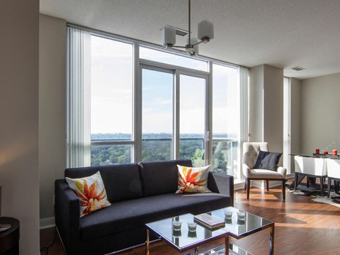A living room with a black couch and a glass coffee table.