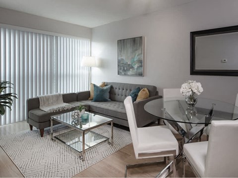 A modern living room with a glass table and white chairs.