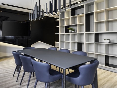 a long black table with blue chairs in front of a white bookshelf