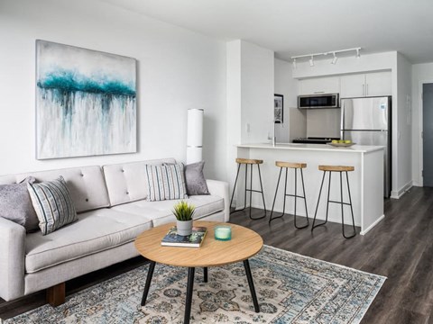 A living room with a couch, a table, and a painting on the wall.