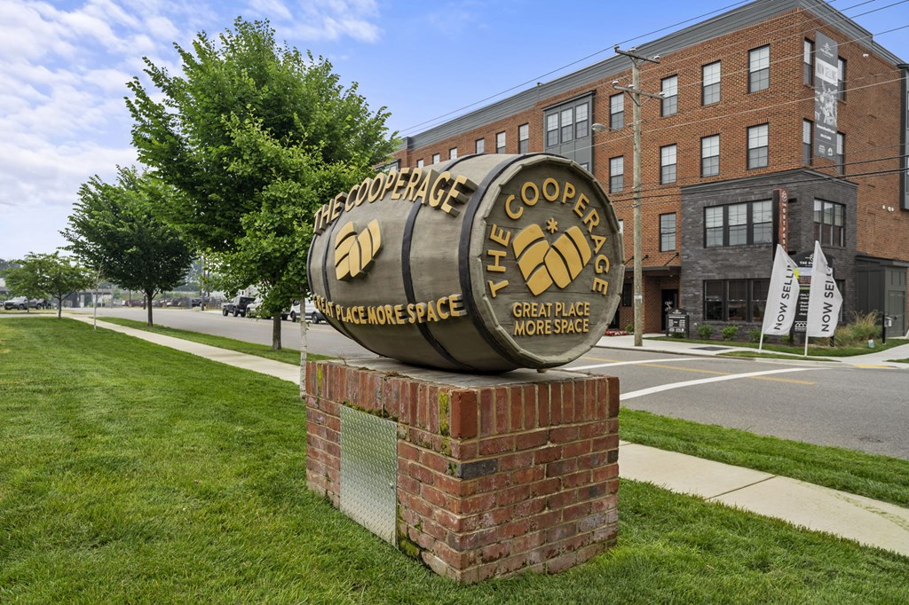 a large metal barrel sign in front of a brick building