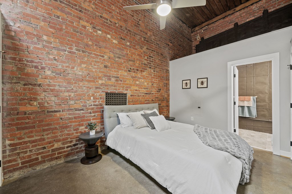 a bedroom with a bed and a exposed brick wall