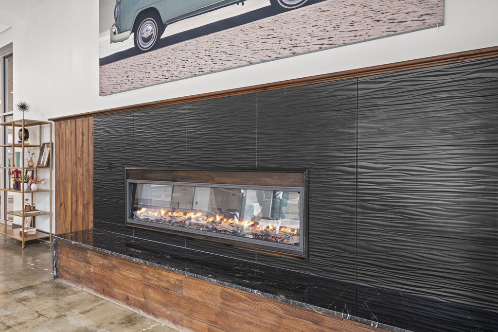 a fireplace with a wooden mantle and a painting of a car on the wall above it  at The Icon, Richmond, VA 23230