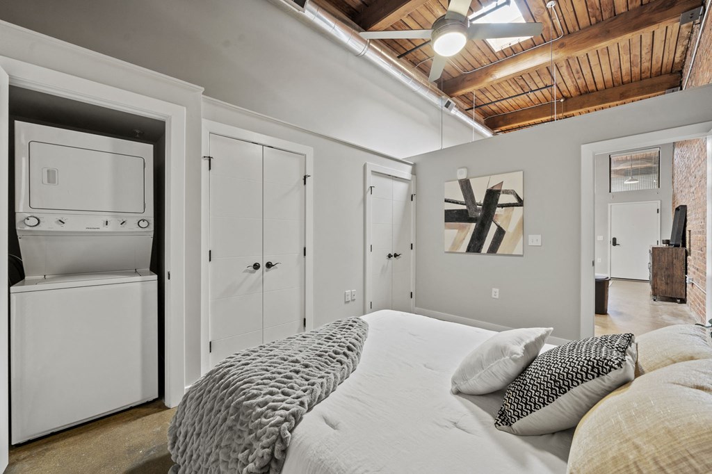 a bedroom with a large bed and a closet with a washer and dryer