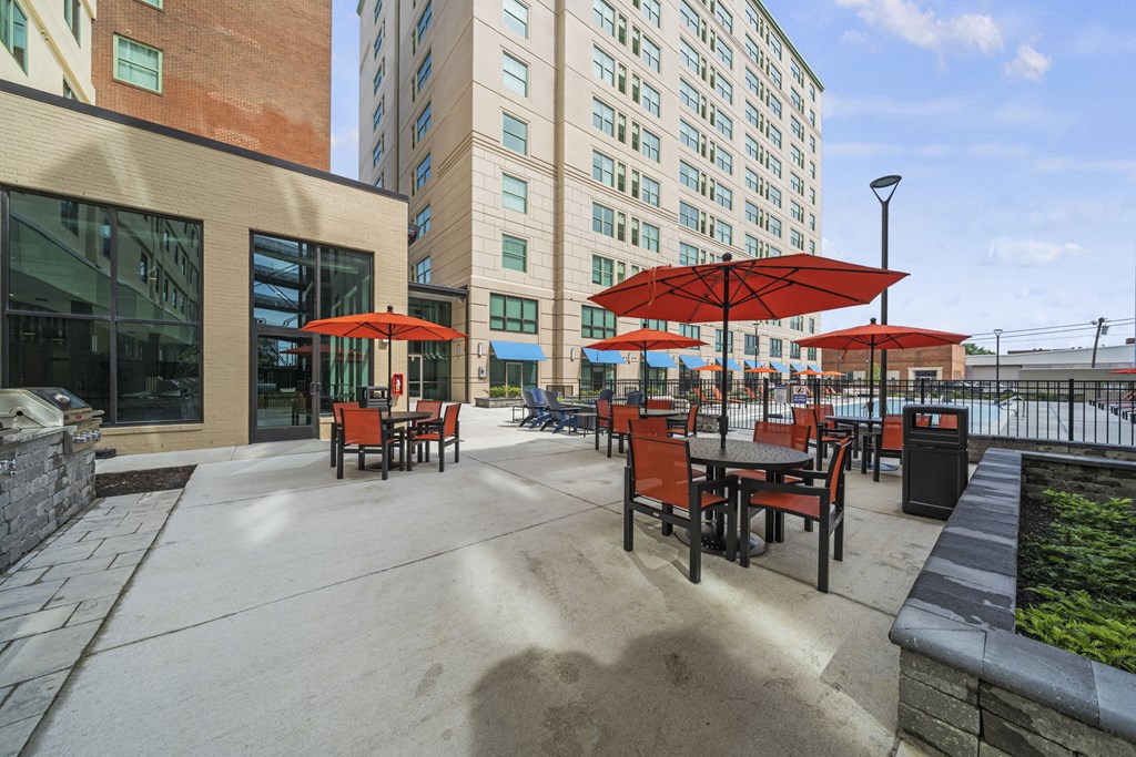 a patio with tables and umbrella  at The Icon, Richmond, VA, 23230s and a building in the background at The Icon in Richmond, VA 23230