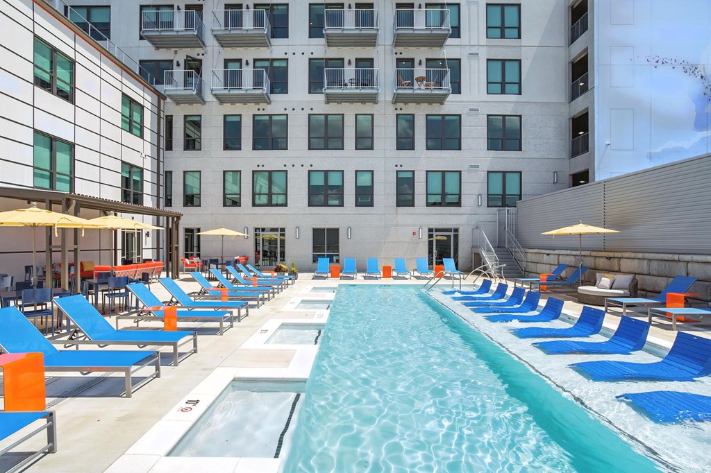 A long rectangular pool with blue and white loungers on either side.