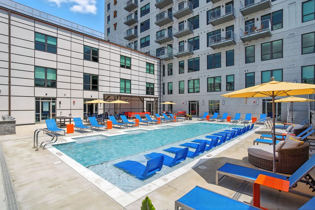 A large pool with blue and brown loungers and a yellow umbrella.