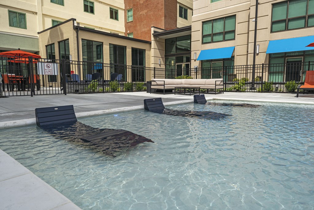 a pool with lounge chairs and umbrellas in front of a building at The Icon, Richmond, VA 23230