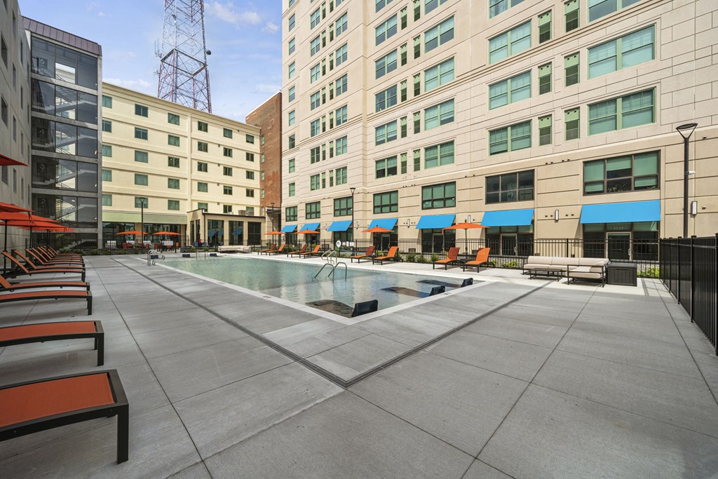 a pool area with lounge chairs and umbrellas in front of a tall building  at The Icon, Richmond, VA 23230