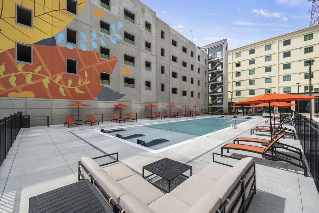 a pool with lounge chairs and umbrellas in front of a building at The Icon in Richmond, VA 23230
