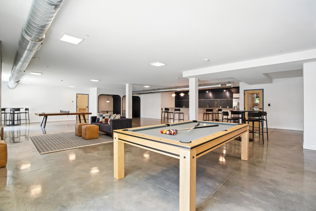 A pool table is in the middle of a room with a concrete floor.