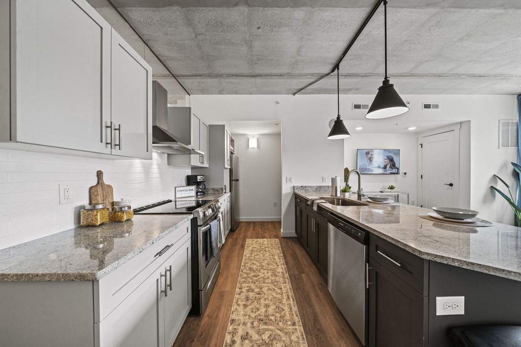 a kitchen with white cabinets and a large island with granite countertops at The Icon, Richmond, VA 23230