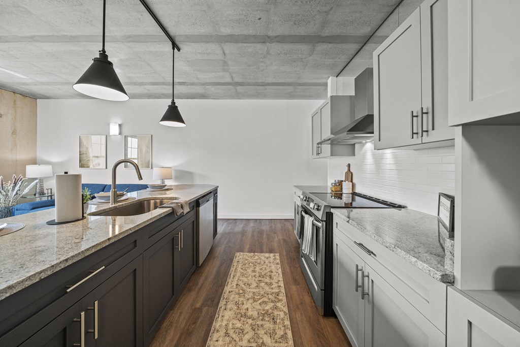 a kitchen with white cabinets and gray countertops at The Icon, Richmond, VA 23230