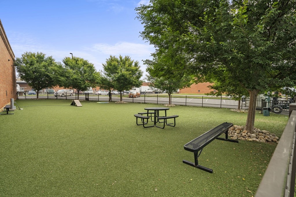 a picnic table and bench sit in a grassy area with trees and a playground in the