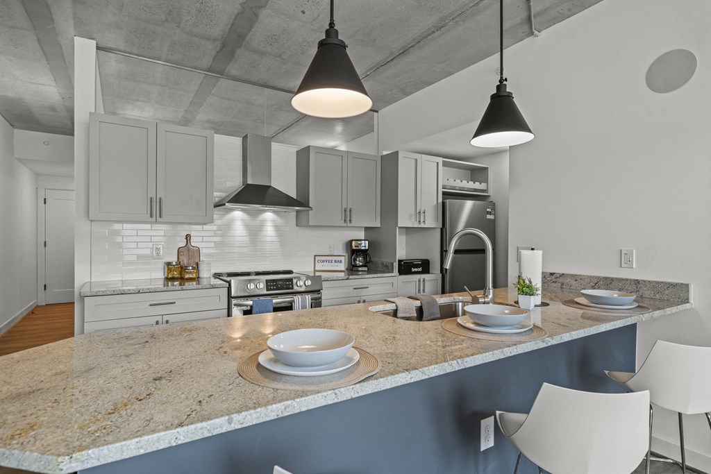 a kitchen with white cabinets and a large island with a granite countertop  at The Icon, Richmond, VA 23230