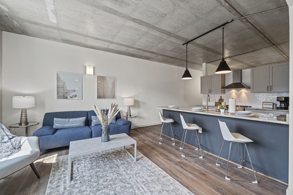 a living area with a sofa coffee table and a kitchen with a breakfast bar  at The Icon, Richmond, VA 23230