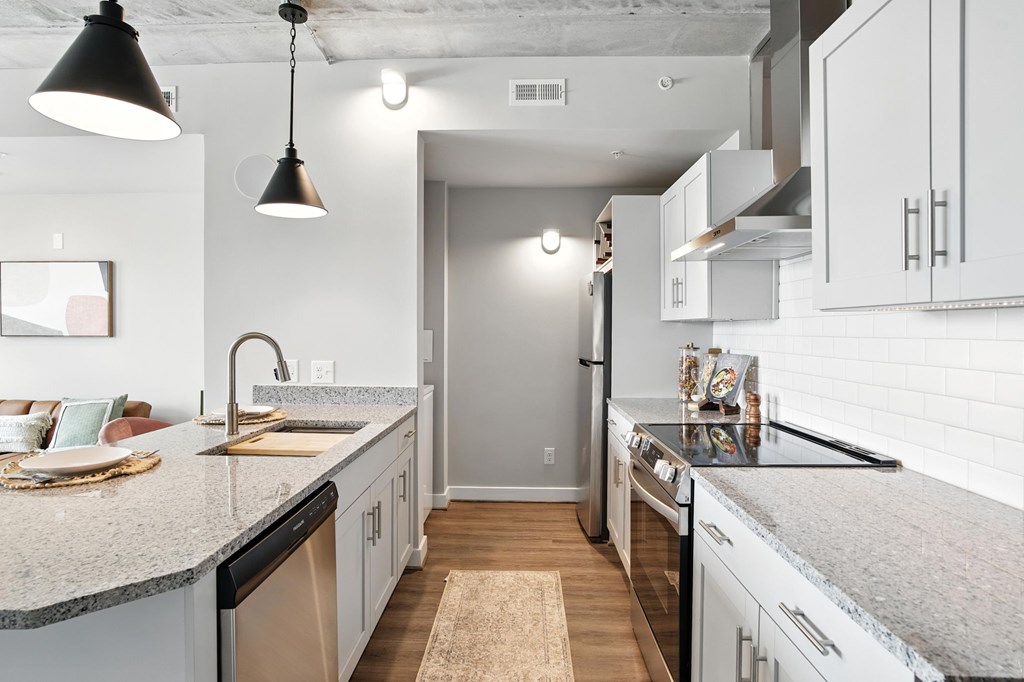 A kitchen with a white counter top and a rug on the floor.