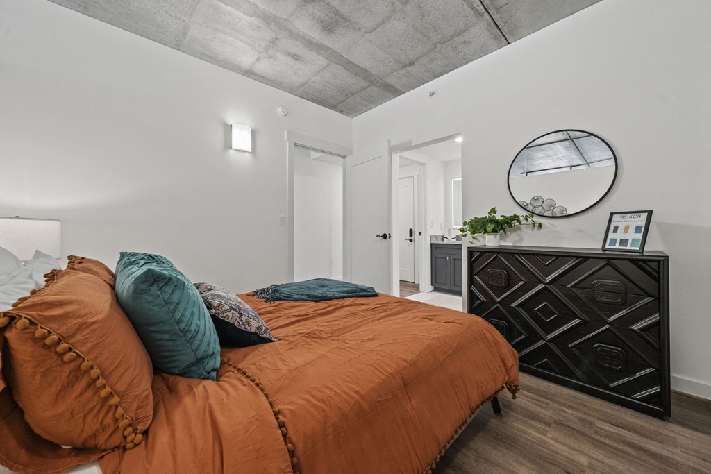 a bedroom with a large bed and a dresser with a mirror  at The Icon, Richmond, VA 23230