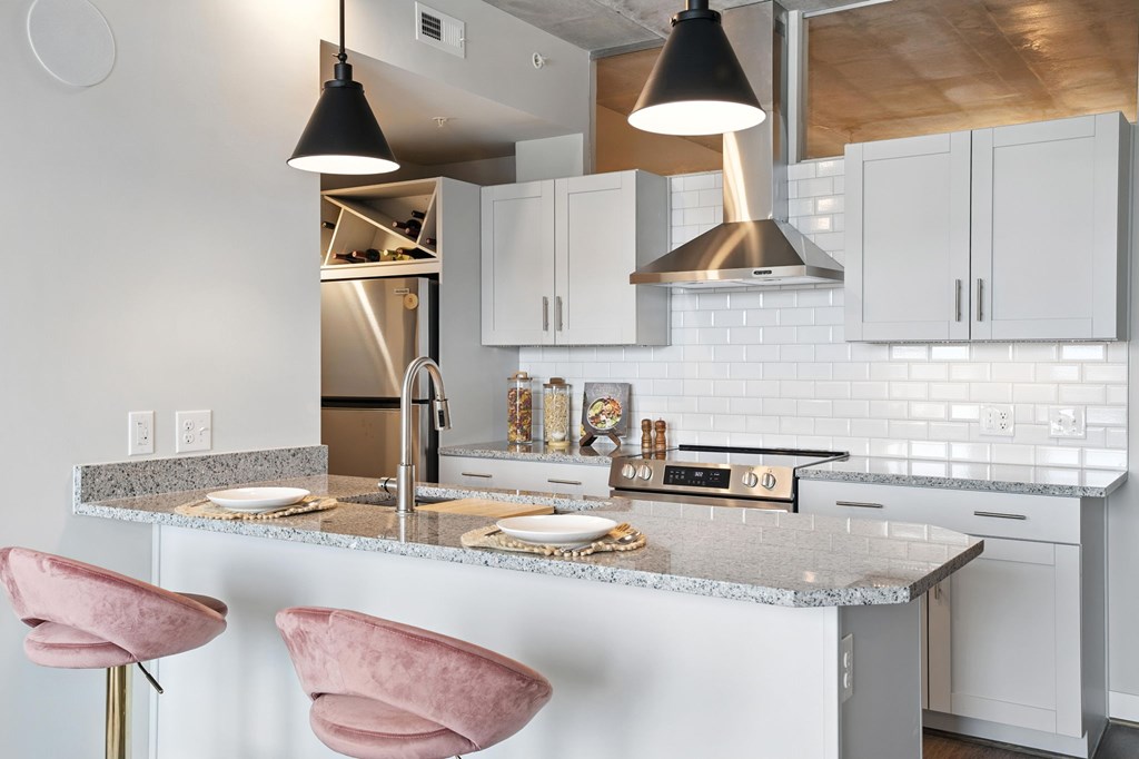 A kitchen with a marble countertop and pink chairs.