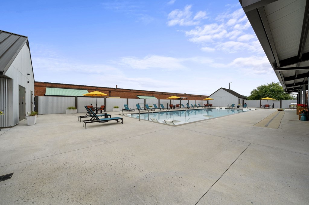 a large pool with lounge chairs and umbrellas in front of a building