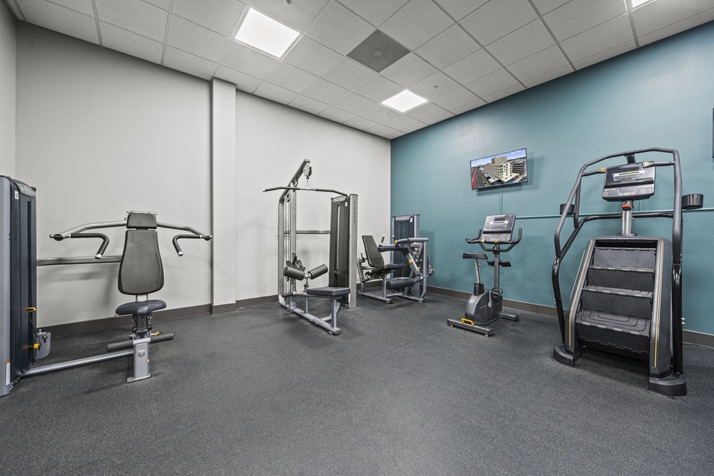 a large room with exercise equipment and a wall mounted tv  at The Icon, Richmond, VA 23230