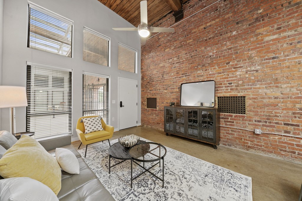 a living room with a large brick wall and a ceiling fan
