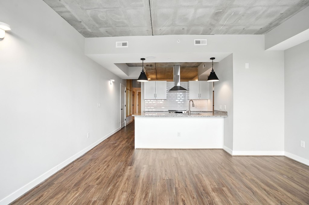 A kitchen area with a white counter and a wooden floor.