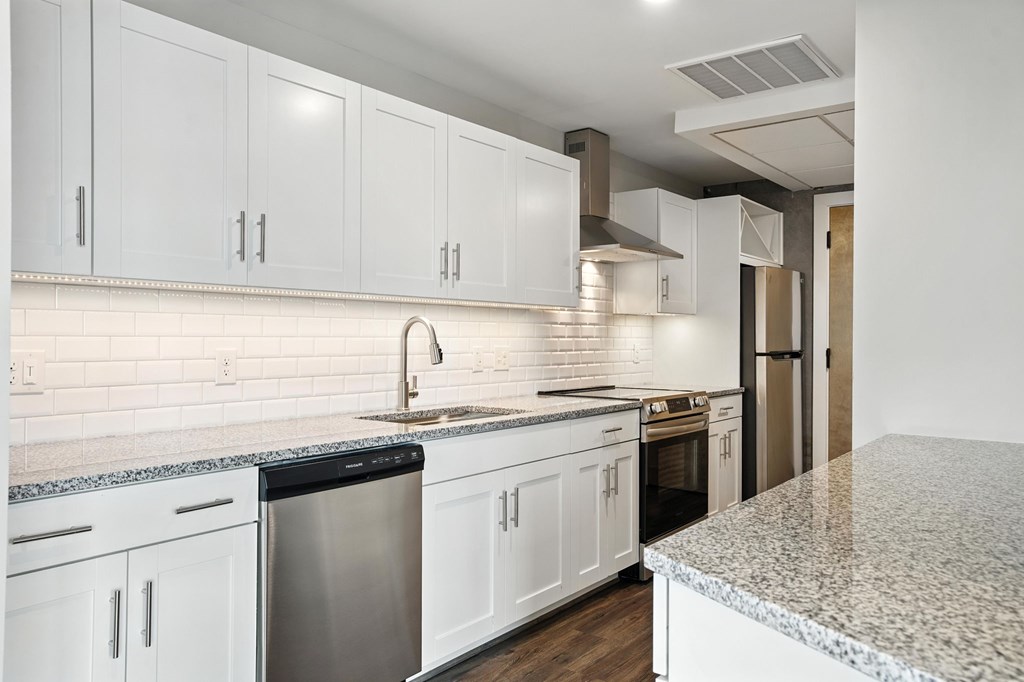 A kitchen with white cabinets and a granite countertop.