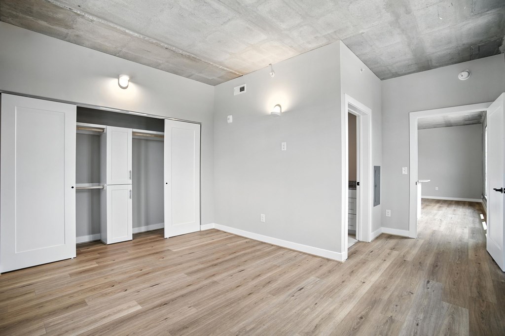 A room with white walls and wooden floors has two open doors.
