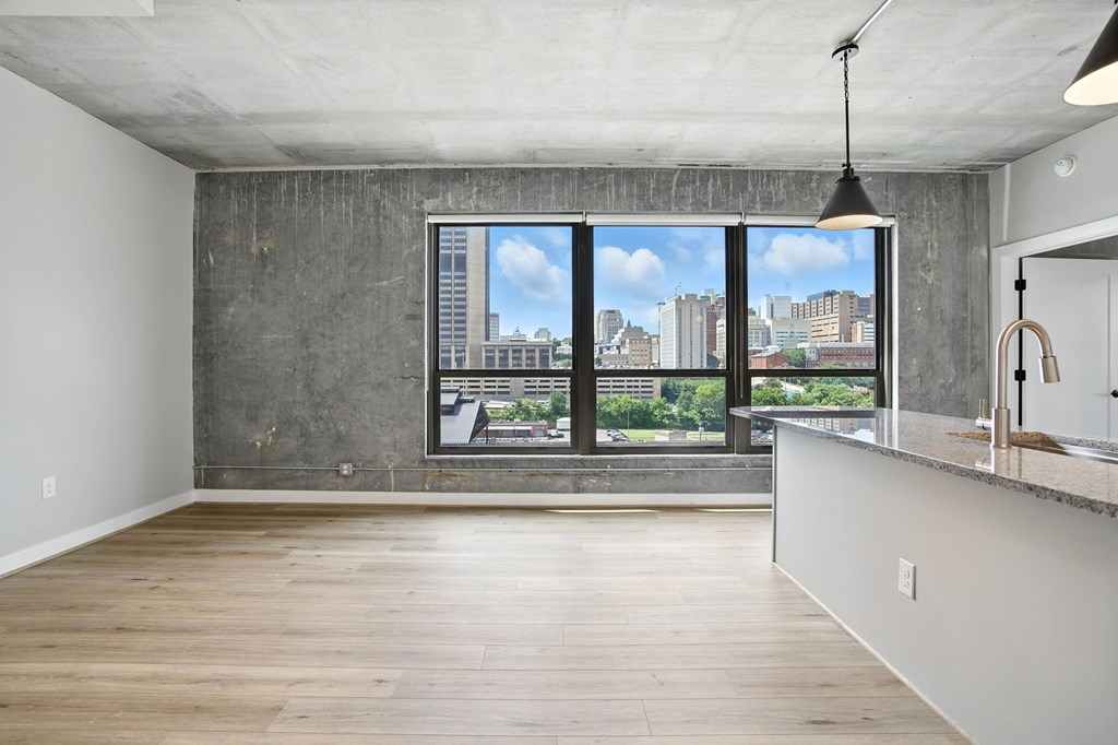 A large empty room with a view of the city through the windows.