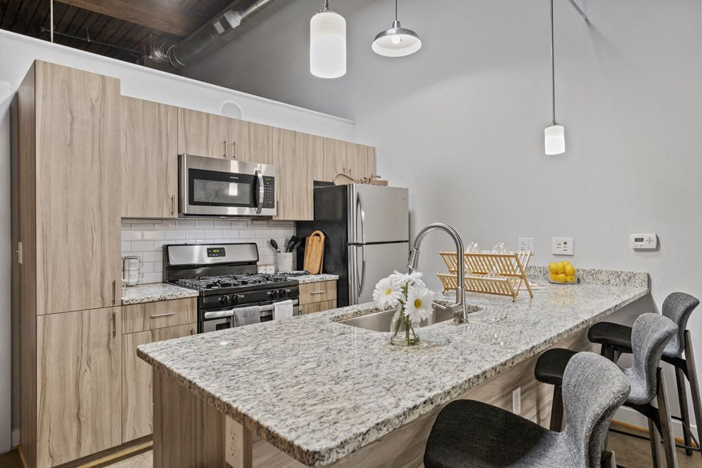 a kitchen with a large island with granite countertops and stainless steel appliances