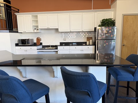 A kitchen with a refrigerator, two chairs and a table.