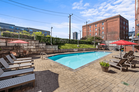 a swimming pool with chairs and umbrellas next to a building