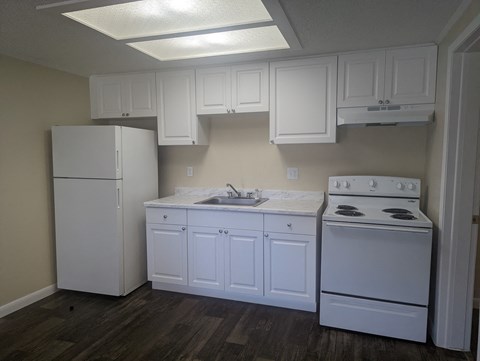 a kitchen with white cabinets and appliances and a white refrigerator
