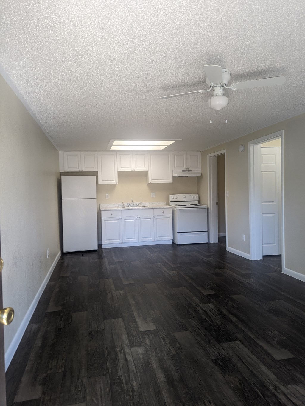 an empty kitchen with white cabinets and a ceiling fan