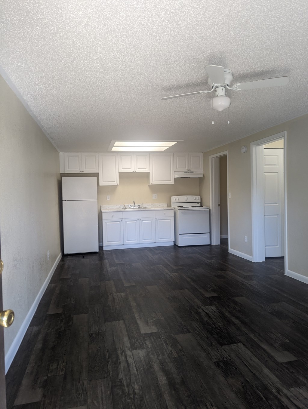 an empty kitchen with white cabinets and a ceiling fan