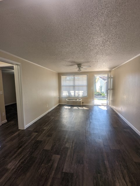 an empty living room with wood floors and a window