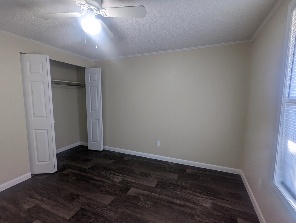 an empty living room with wood floors and a ceiling fan