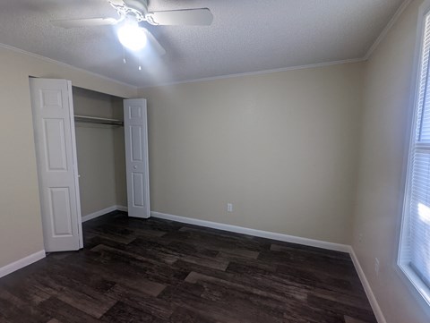 an empty living room with wood floors and a ceiling fan