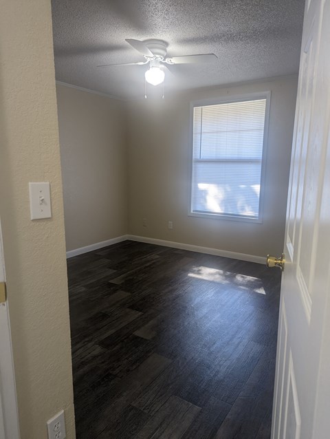 an empty bedroom with a ceiling fan and a window