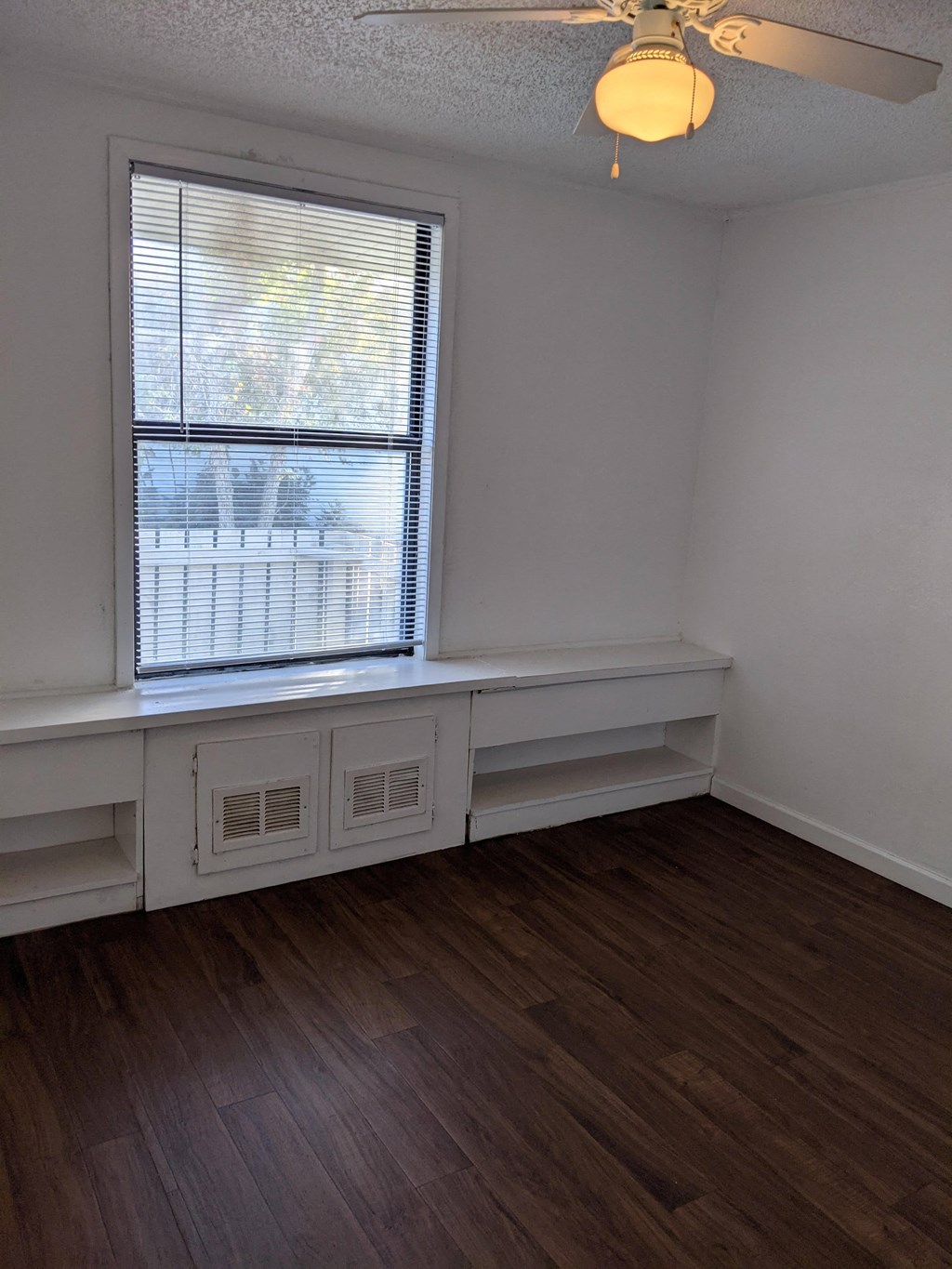 the living room of an empty house with wooden floors and a window